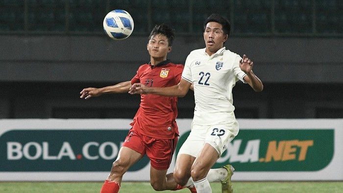 Pesepak bola Timnas Laos U-19 Vongsakda Chanthaleauxy (kiri) berebut bola dengan pesepak bola Timnas Thailand U-19 Phanthamit Praphanth (kanan) dalam laga semifinal Piala AFF U19 2022 di Stadion Patriot Chandrabhaga, Bekasi, Jawa Barat, Rabu (13/7/2022). Skor sementara Laos unggul 1-0. ANTARA FOTO/Fakhri Hermansyah/tom.