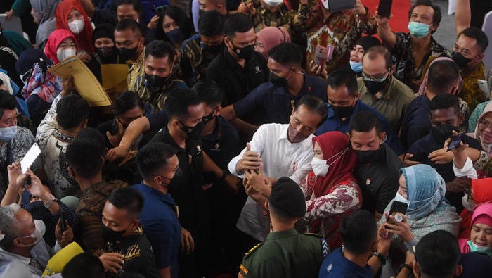 Presiden Joko Widodo (tengah) melayani ajakan berswafoto warga usai acara pemberian Nomor Induk Berusaha (NIB) pelaku Usaha Mikro Kecil (UMK) perseorangan tahun 2022 di Jakarta, Rabu (13/7/2022). Presiden Joko Widodo memberikan Nomor Induk Berusaha (NIB) ke 2.500 pelaku UMK dari Provinsi DKI Jakarta dan sekitarnya. ANTARA FOTO/Akbar Nugroho Gumay/rwa.