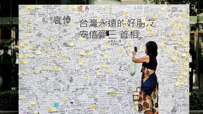 A woman takes photographs of condolence messages for former Japanese prime minister Shinzo Abe in front of the Japan-Taiwan Exchange Association office in Taipei on July 11, 2022. - Abe, Japan's longest serving prime minister, was fatally shot during a campaign stop on July 8 in an exceedingly rare gun crime in one of the world's safest countries. (Photo by Sam Yeh / AFP) (Photo by SAM YEH/AFP via Getty Images)
