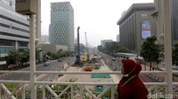Seorang warga melintasi jembatan penyeberangan orang (JPO) dengan latar pembangunan MRT Jakarta fase 2A di Jalan MH Thamrin, Jakarta Pusat, Rabu (13/7/2022).