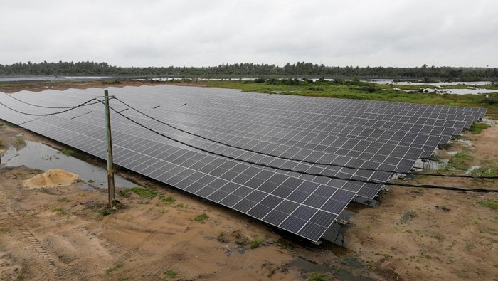 Solar power technicians walk past the fishing pond at the Atlantic Shrimpers farm in Badagry, Lagos, Nigeria July 5, 2022. REUTERS/Temilade Adelaja