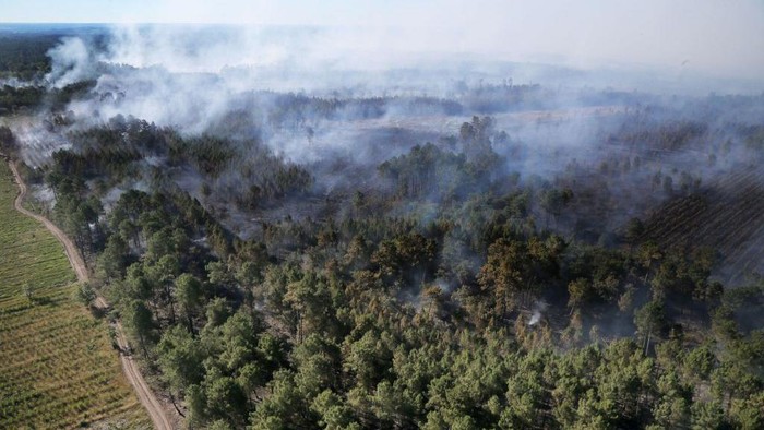 Berjibaku Padamkan Kebakaran Hutan di Prancis A Canadair firefighting aircraft dumps water over a wildfire in Landiras, southwestern France, on July 13, 2022. - Two fires have burned nearly 1,700 hectares of pine trees in Gironde on July 13, forcing the evacuation of 6,000 campers. A heat wave in Western Europe is fuelling wildfires across vast stretches of forestland. (Photo by Laurent THEILLET / various sources / AFP) (Photo by LAURENT THEILLET/AFP via Getty Images)