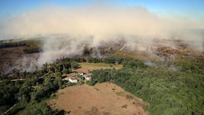 A Canadair firefighting aircraft dumps water over a wildfire in Landiras, southwestern France, on July 13, 2022. - Two fires have burned nearly 1,700 hectares of pine trees in Gironde on July 13, forcing the evacuation of 6,000 campers. A heat wave in Western Europe is fuelling wildfires across vast stretches of forestland. (Photo by Laurent THEILLET / various sources / AFP) (Photo by LAURENT THEILLET/AFP via Getty Images)