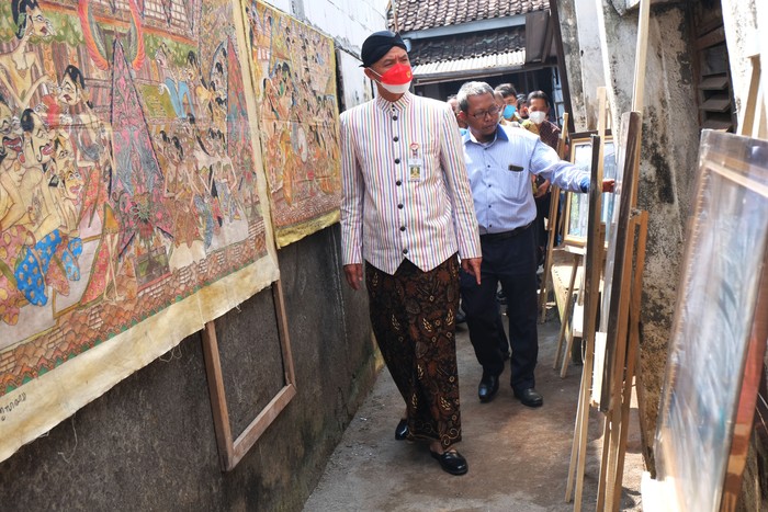 Gubernur Jawa Tengah Ganjar Pranowo mengamati hasil karya maestro lukis Wayang Beber Hermin Istiariningsih saat mengunjungi kediamannya di Kampung Wonosaren, Jagalan, Solo, Jawa Tengah, Kamis (14/7/2022). Kunjungan tersebut untuk meninjau bantuan Rumah Tidak Layak Huni (RTLH) sehingga memenuhi kebutuhan rumah tinggal yang layak huni bagi keluarga Hermin Istiariningsih. ANTARAFOTO/Maulana Surya/hp.