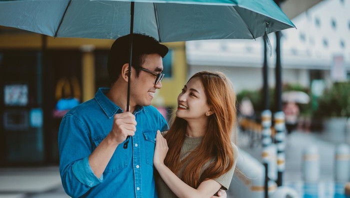 Young Asian couple walking in the rain
