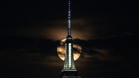 Bulan purnama yang dikenal sebagai Buck Moon muncul di atas cakrawala Kota New York, seperti yang terlihat dari Weehawken, New Jersey, AS, Rabu, (13/7/2022). REUTERS/Jeenah Moon