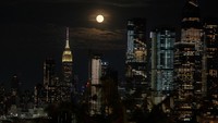 Bulan purnama yang dikenal sebagai Buck Moon muncul di atas cakrawala Kota New York, seperti yang terlihat dari Weehawken, New Jersey, AS, Rabu, (13/7/2022). REUTERS/Jeenah Moon
