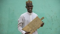 Tampak seorang pemuda memegang papan kayu yang bertuliskan ayat-ayat Al-Quran di Khartoum, Ibu Kota Sudan.