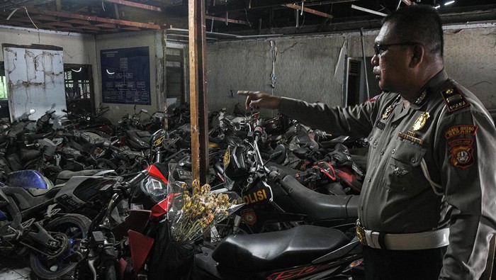 Petugas Kepolisian menunjukkan sepeda motor terbengkalai di kantor Laka Lantas Polres Metro Bekasi, Cikarang, Kabupaten Bekasi, Jawa Barat, Kamis (14/7/2022). Sebanyak ribuan motor bekas kecelakaan, sitaan dan hasil tindak kejahatan dari tahun 2004 berada di penampungan ini dan belum diambil pemiliknya. ANTARA FOTO/ Fakhri Hermansyah