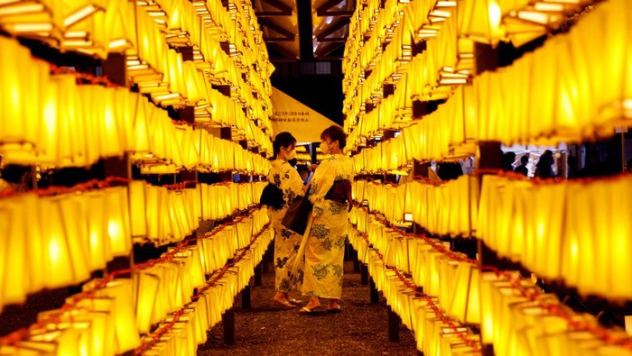 Women in yukata, or casual summer kimonos, wearing protective masks amid the coronavirus disease (COVID-19) outbreak, look around lanterns during the annual Mitama Festival at the Yasukuni Shrine, where more than 2.4 million war dead are enshrined, in Tokyo, Japan, July 13, 2022. REUTERS/Kim Kyung-Hoon     TPX IMAGES OF THE DAY
