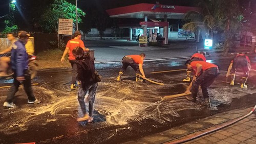 Personil Damkartan Karangasem membersihkan tumpahan solar yang tercecer di Jalan Raya Ahmad Yani, Subagan, Karangasem, Kamis (14/7/2022).