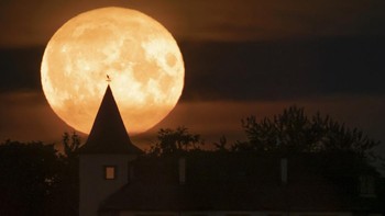 Pemandangan bulan purnama yang terlihat di balik sebuah rumah yang berada di Putilovo, 70 kilometer di timur St. Petersburg, Rusia, Rabu (13/7/2022) malam. (AP Photo/Dmitri Lovetsky).  