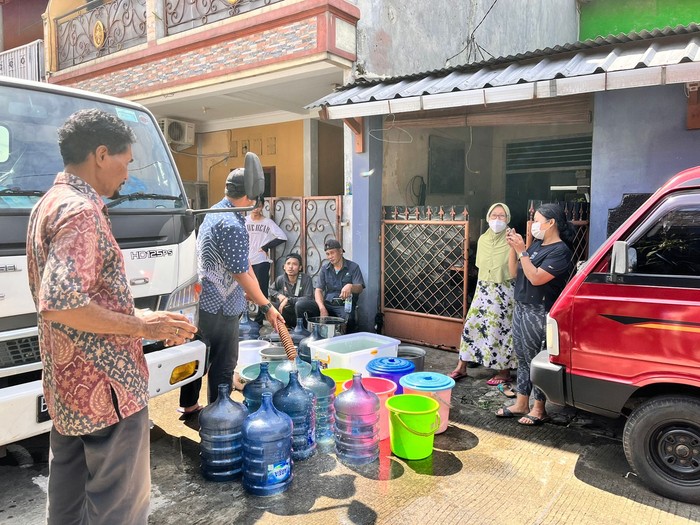 Warga Kompleks Marinir, Pancoranmas Depok mengantre air bersih dari tangki gegera gangguan air PAM, Kamis (14/7/2022).