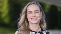 Brie Larson tampil dengan croptop berkilau keemasan dengan mantel hitam beraksen bunga-bunga emas. (Foto: Laurent Viteur/Getty Images) 