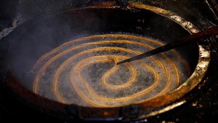 A worker pours dough into a large vat of frying oil to make traditional Spanish 'Churros' in the Eijalde family run 'Churreria La Manueta' in central Pamplona, Spain, July 12, 2022. REUTERS/Juan Medina