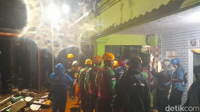 Hujan deras mengakibatkan dinding rumah warga di Kelurahan Curug, Kota Bogor ambrol. Seorang wanita tertimbun dan masih dalam proses evakuasi. (M Sholihin/detikcom)