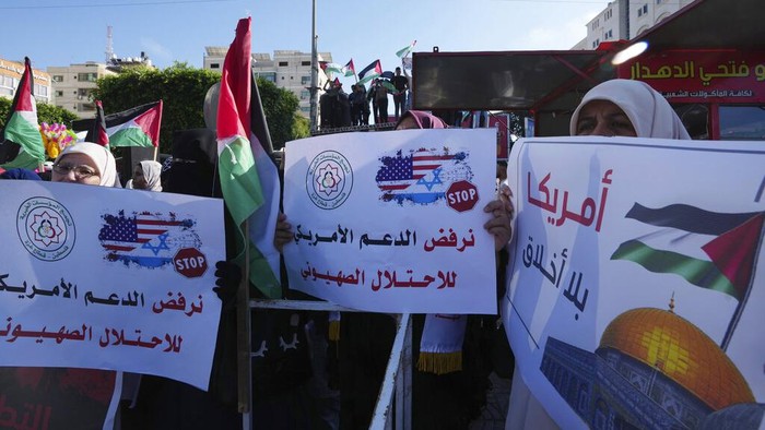Kunjungan Biden ke Israel Disambut Unjukrasa di Jalur Gaza Women wave their national flags while holding placards with Arabic that reads