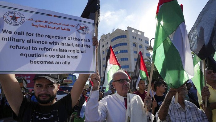 Kunjungan Biden ke Israel Disambut Unjukrasa di Jalur Gaza Women wave their national flags while holding placards with Arabic that reads