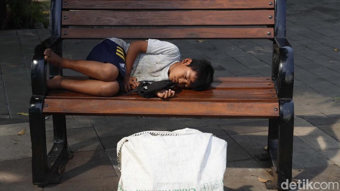Seorang bocah berusia belasan tahun tertidur pulas di kursi trotoar Jalan Senopati, Blok S, Jakarta, Jumat (15/7). Bocah ini kelelahan setelah bekerja sebagai pemulung.