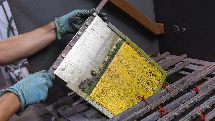 Melihat Proses Pembuatan Emas Batangan A staff takes a sample of melted gold out of a smelter into a mould of a bar at a plant of gold and silver refiner and bar manufacturer Argor-Heraeus in Mendrisio, Switzerland, July 13, 2022. REUTERS/Denis Balibouse