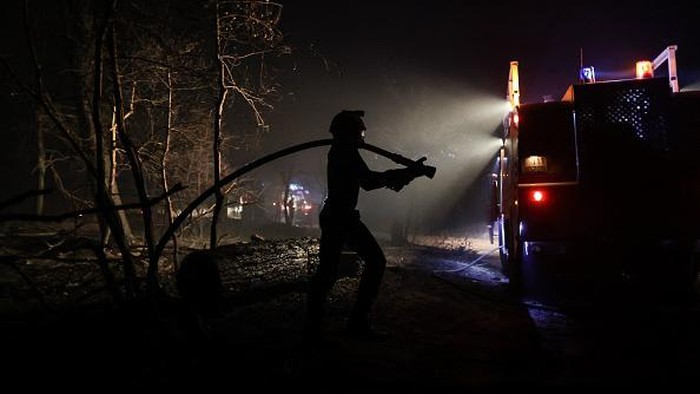 Restoran Ini Hancur Dilalap Kebakaran Hutan di Prancis A firefighter spreads water as a wildfire extends in the area close to the beach of Cazaux lac, near La Teste-de-Buch, southwestern France, on July 15, 2022. - In a context of strong heat on the southern half of the country, the firemen still face two aggressive forest fires in Gironde, with more than 5.000 hectares burned and more than 10.000 people evacuated since July 12, 2022, and fight from now on a
