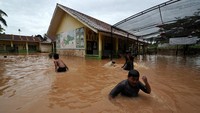 Sejumlah anak bermain air saat banjir menggenangi SDN 98 Kota Jambi di Kota Baru, Jambi, Jumat (15/7/2022).