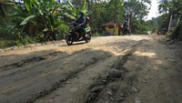 Warga mengendarai motor melintasi jalan desa yang rusak di Bayat, Klaten, Jawa Tengah, Jumat (15/7/2022).