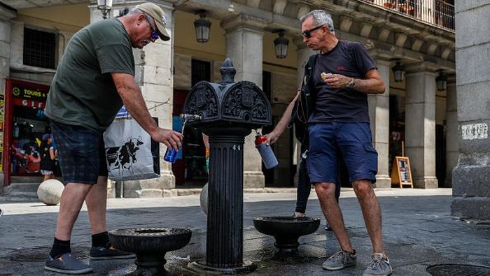 Warga Madrid Berebut Minum dari Keran di Tengah Cuaca Super Terik MADRID, SPAIN - JULY 14: People refill their water bottles at a fountain as they attempt to cool off at Plaza Mayor as temperatures continue to soar on July 14, 2022 in Madrid, Spain. Europe is currently experiencing the most sustained period of extreme hot weather in 50 years. (Photo by Pablo Blazquez Dominguez/Getty Images)
