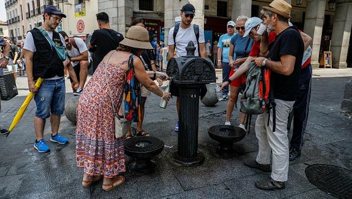 Warga Madrid Berebut Minum dari Keran di Tengah Cuaca Super Terik MADRID, SPAIN - JULY 14: People refill their water bottles at a fountain as they attempt to cool off at Plaza Mayor as temperatures continue to soar on July 14, 2022 in Madrid, Spain. Europe is currently experiencing the most sustained period of extreme hot weather in 50 years. (Photo by Pablo Blazquez Dominguez/Getty Images)