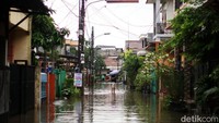 Warga memilih bertahan dengan memantau kondisi banjir dari depan rumahnya.