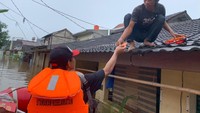 Tampak ada warga yang mengambil makanan dari atap rumah. Makanan tersebut dibagikan oleh Karang Taruna setempat dengan menggunakan perahu karet. (Mulia-detikcom)