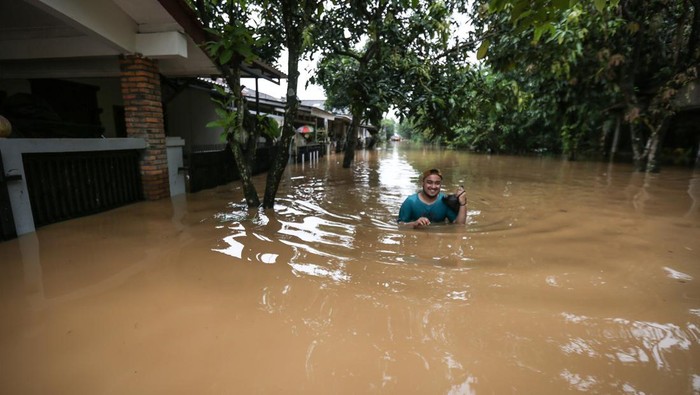 Banjir Setinggi Dada Rendam Villa Pamulang Depok Seorang warga berjalan saat banjir di Villa Pamulang, Pondok Petir, Depok, Jawa Barat, Sabtu (16/7/2022). Tanggul aliran sungai jebol dan hujan deras yang mengguyur pada Jumat (15/7) malam hingga pagi hari mambuat air sungai di sekitar lokasi meluap menyebabkan banjir dengan ketinggian 1 meter.