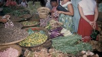 Begitu pun dengan foto yang satu ini. Seorang wanita berbelanja bawang merah. Bawang merah itu kemudian akan dikemas pakai anyaman bambu. Foto: Lib.UWM - Forman Harrison