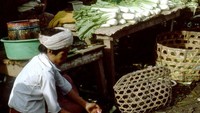 Foto ini adalah suasana pasar tradisional di Bali. Terlihat pedagang menjual sawi putih dan pedagang lainnya membersihkan daging ayam. Foto: Blake Smith 