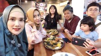 Wanita 42 tahun ini sedang makan seafood bareng keluarga besarnya. Tampak ada berbagai seafood di atas meja yang siap disantap.