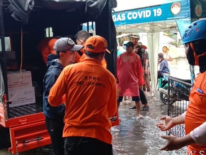 Petugas dari BNPB dan BPBD DKI membagikan bantuan untuk warga terdampak banjir (dok. BNPB)