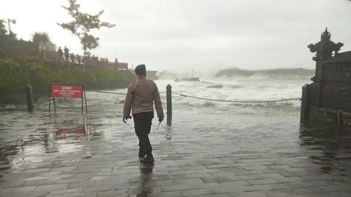 Petugas Satpolair Polres Tabanan berpatroli pada garis peringatan dilarang melintas yang terpasang di objek wisata Tanah Lot, Sabtu (16/7/2022).