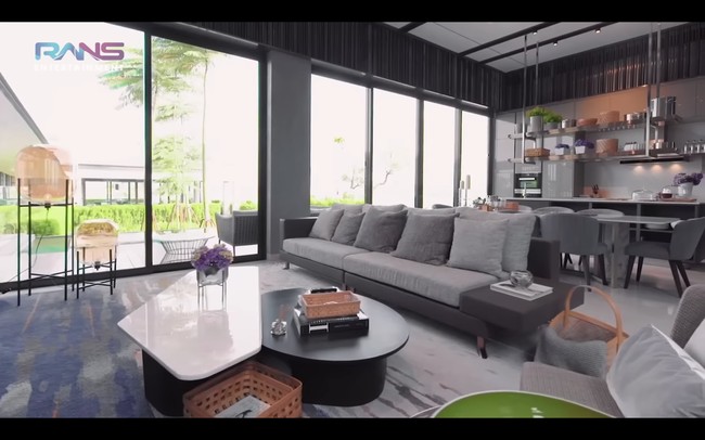 Dan di sebelah kiri lift, terdapat ruang televisi yang menyatu dengan kitchen bar. Seluruh furnitur bernuansa abu-abu. Meskipun terletak di tengah kota, rumah berlantai tiga itu memiliki pemandangan danau. Foto: dok. YouTube Rans Entertainment