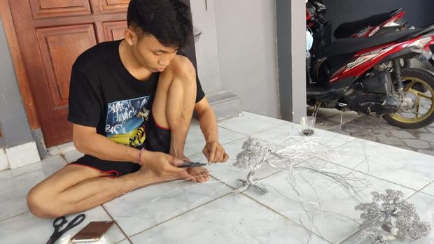 Tri Budi Santoso saat membuat miniatur bonsai dari kawat aluminium.