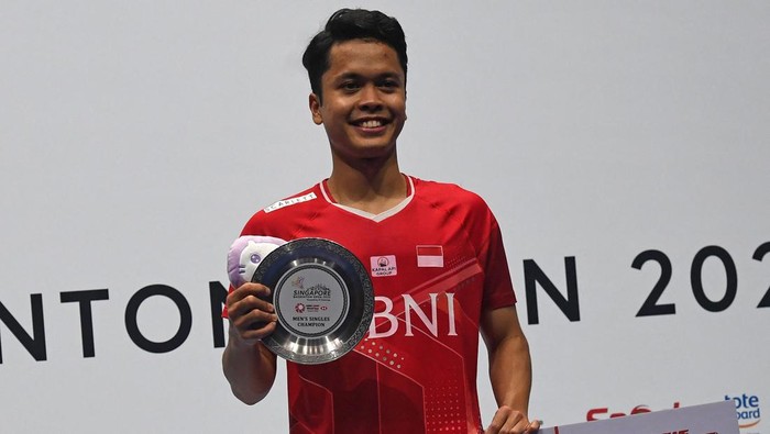 Indonesia's Anthony Sinisuka Ginting celebrates on the podium after defeating Japan's Kodai Naraoka during the men's singles final at the Singapore Open badminton tournament in Singapore on July 17, 2022. (Photo by ROSLAN RAHMAN / AFP) (Photo by ROSLAN RAHMAN/AFP via Getty Images)