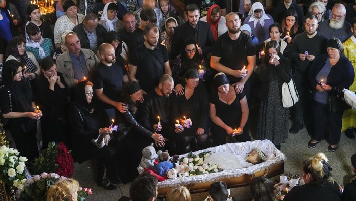 Relatives and friends pay their last respects to Liza, a 4-year-old girl killed by a Russian attack, during a mourning ceremony in an Orthodox church in Vinnytsia, Ukraine, Sunday, July 17, 2022. Wearing a blue denim jacket with flowers, Liza was among 23 people killed, including 2 boys aged 7 and 8, in Thursday's missile strike in Vinnytsia. Her mother, Iryna Dmytrieva, was among the scores injured. (AP Photo/Efrem Lukatsky)