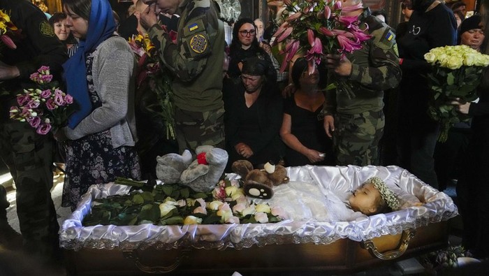 Relatives and friends pay their last respects to Liza, a 4-year-old girl killed by a Russian attack, during a mourning ceremony in an Orthodox church in Vinnytsia, Ukraine, Sunday, July 17, 2022. Wearing a blue denim jacket with flowers, Liza was among 23 people killed, including 2 boys aged 7 and 8, in Thursday's missile strike in Vinnytsia. Her mother, Iryna Dmytrieva, was among the scores injured. (AP Photo/Efrem Lukatsky)