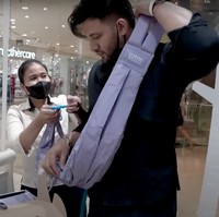 Dengan dibantu oleh pelayan di sana, Ammar tampak mencoba kain gendongan yang dipilih oleh sang istri. Gimana, sudah cocok jadi ayah 2 anak belum nih? Foto: YouTube/Aish TV
