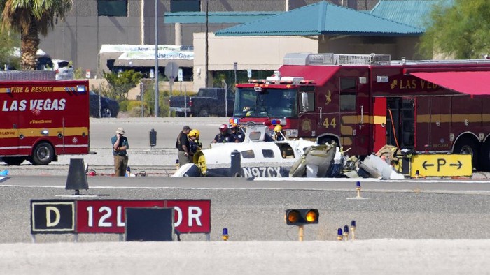 Officials investigate the wreckage of a plane at the site of a fatal crash at the North Las Vegas Airport, Sunday, July 17, 2022, in North Las Vegas, Nev. Authorities say several people are dead after two small planes collided at North Las Vegas Airport. (AP Photo/John Locher)
