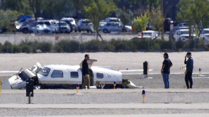 Officials investigate the wreckage of a plane at the site of a fatal crash at the North Las Vegas Airport, Sunday, July 17, 2022, in North Las Vegas, Nev. Authorities say several people are dead after two small planes collided at North Las Vegas Airport. (AP Photo/John Locher)