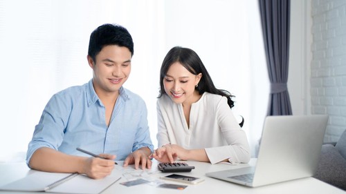 Asian couples are calculating their expenses with a calculator. They are happy.