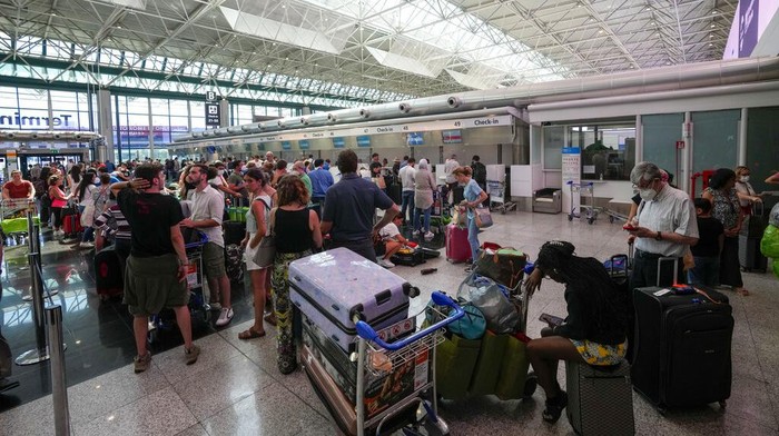 Pegawai Maskapai Italia Mogok Kerja, Ribuan Penumpang Terlantar Passengers rest next to their luggage in Rome's Leonardo Da Vinci international airport, Sunday, July 17, 2022. Several hundred flights were canceled in Italy Sunday, a peak vacation travel day, because of four-hour walkouts involving employees of low-cost airlines as well as air traffic controllers. (AP Photo/Andrew Medichini)