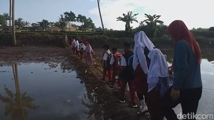 Jembatan terputus akibat banjir bandang membuat siswa SD di Garut menyebrang dengan menggunakan perahu karet