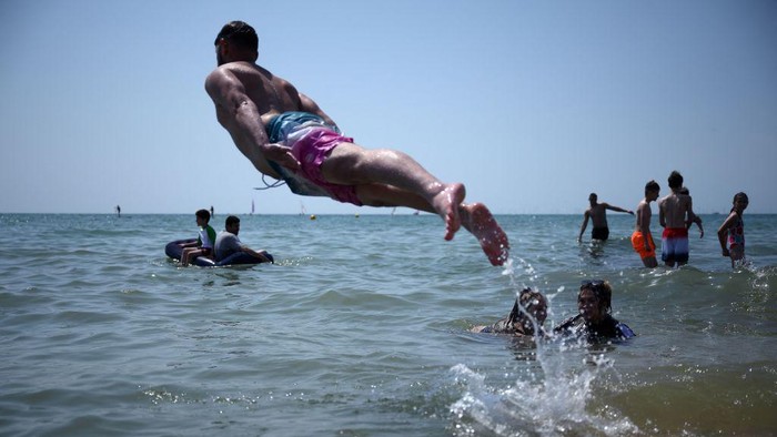 Ribuan Warga Inggris Padati Pantai di Tengah Gelombang Panas Beachgoers enjoy the sun and the sea on the beach at Brighton, southern England on July 17, 2022. - The UK's meteorological agency on Friday issued its first ever