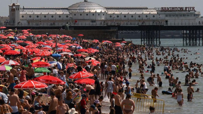 Ribuan Warga Inggris Padati Pantai di Tengah Gelombang Panas Beachgoers enjoy the sun and the sea on the beach at Brighton, southern England on July 17, 2022. - The UK's meteorological agency on Friday issued its first ever